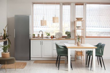 Yemek masası, beyaz tezgah ve modern buzdolabı olan şık bir mutfak.