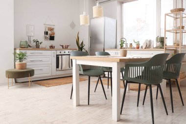 Yemek masası, beyaz tezgah ve modern buzdolabı olan şık bir mutfak.