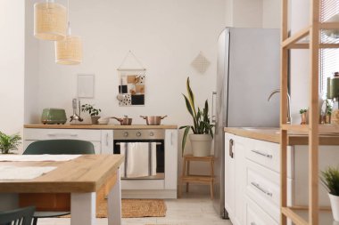 Yemek masası, beyaz tezgah ve modern buzdolabı olan şık bir mutfak.