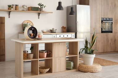 Ada masası, ev bitkileri ve modern buzdolabı olan şık bir mutfak.