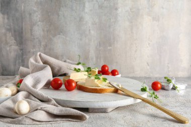 Lezzetli işlenmiş peynir üçgenleriyle beyaz ahşap ekmek dilimleri ve gri arka planda mikro yeşil