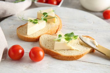 Lezzetli işlenmiş peynir üçgenleriyle beyaz ahşap ekmek dilimleri ve gri arka planda mikro yeşil