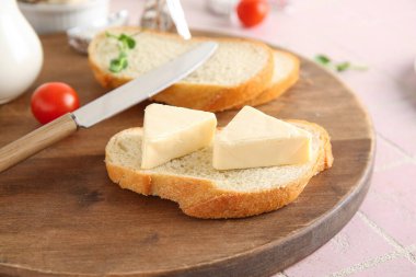 Ahşap tahta ekmek dilimi üzerinde işlenmiş lezzetli peynir üçgenleri ve pembe fayanslar.