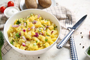 Beyaz arka planda soğanlı bir tabak lezzetli patates salatası.