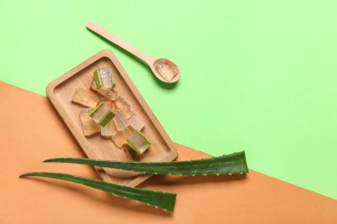 Taze aloe jeli ahşap tahta, yapraklar ve kaşık renkli arka plan