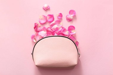Pembe arka planda gül yaprakları olan kozmetik çanta.