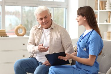 Evdeki kanepede olgun bir adamla çalışan kadın doktor.