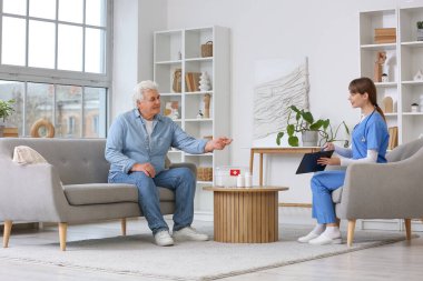 Kadın doktor evde olgun bir adamla çalışıyor.