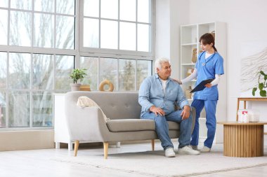 Kadın doktor evde olgun bir adamla çalışıyor.