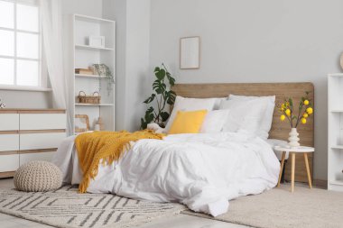 Küçük yatak odasının içinde raf ünitesi, ağaç dalları ve vazoda limonlar var.