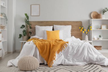 İçinde raf üniteleri, ağaç dalları ve vazoda limonlar olan aydınlık yatak odasının içi.