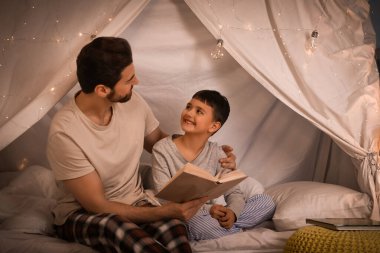 Babası ve küçük oğlu evde kitap okuyorlar.