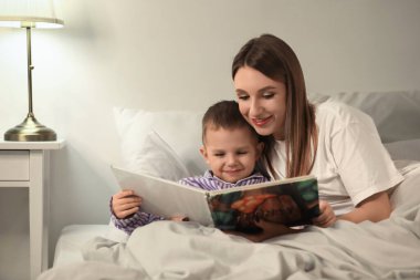 Anne ve küçük oğlu gece yatak odasında masal okuyorlar.