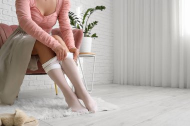 Koltukta otururken beyaz tayt giyen genç kadın.