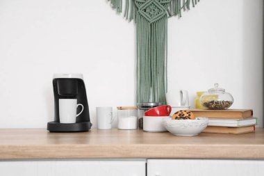 Mutfakta fincanlar ve kitaplarla kahve makinesi.