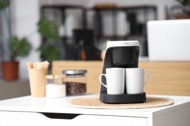 Ofisteki masada fincanlı kahve makinesi, yakın plan.