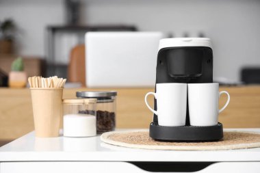 Ofisteki masada fincanlı kahve makinesi, yakın plan.