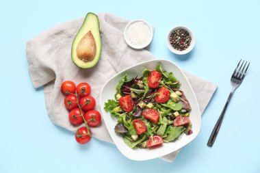 Çeri domatesli avokado salatası ve mavi arka planda baharatlar.