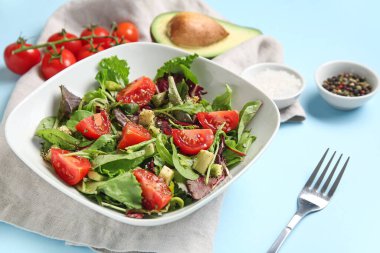 Çeri domatesli avokado salatası ve mavi arka planda baharatlar.