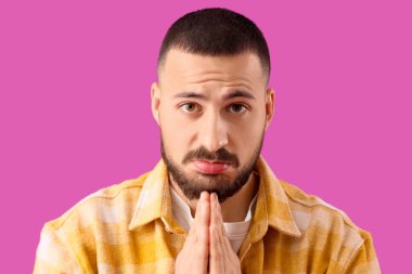 Apologetic young man on violet background, closeup clipart