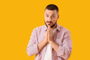 Sarı arka planda özür dileyen genç adam.