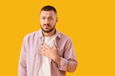 Sarı arka planda özür dileyen genç adam.