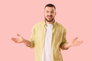 Pembe arka planda özür dileyen genç adam.