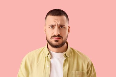 Pembe arka planda özür dileyen genç adam, yakın plan.