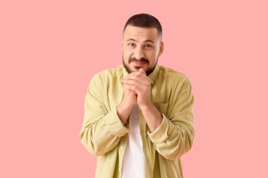 Pembe arka planda özür dileyen genç adam.