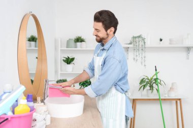 Banyoda musluğu temizleyen yakışıklı adam.