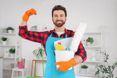 Temizlik malzemeleriyle tuvalette kaslarını gösteren erkek hademe.