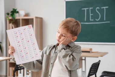 Sınıfta test sonuçlarına sahip üzgün bir öğrenci.