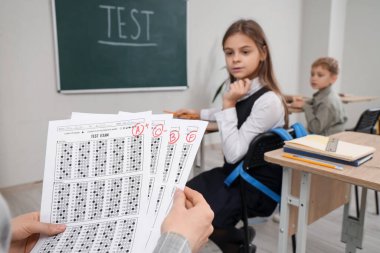 Sınıfta işaretli cevap kağıtları olan öğretmen, yakın plan