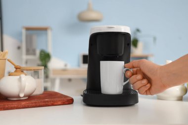 Ofisteki kahve makinesinden fincanı alan kadın, yakın plan.