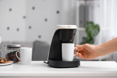 Ofisteki kahve makinesinden fincanı alan kadın, yakın plan.