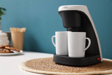 Kahve makinesi mavi duvarın yanındaki masada, yakın plan.