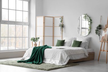 Rahat yatak odasının içinde ayna, resim sehpada ve katlanan ekranda.