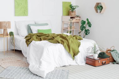 Bavulunda raf ve ev bitkisi olan modern şık bir yatak odası.