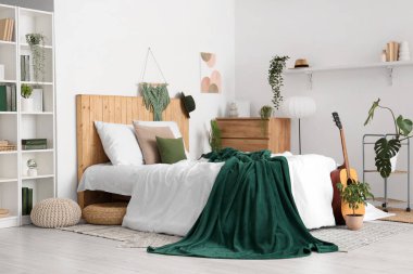 Yatakta yeşil ekose, yatak odasının içinde ev bitkileri ve gitar.