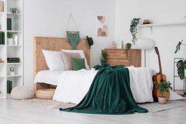 Yatakta yeşil ekose, yatak odasının içinde ev bitkileri ve gitar.