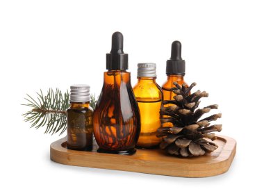 Beyaz zemin üzerinde çam kozalağı ve köknar dalı olan gerekli yağ şişeleri