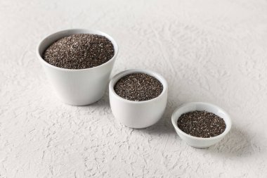 Beyaz arkaplanda chia tohumları olan kaseler