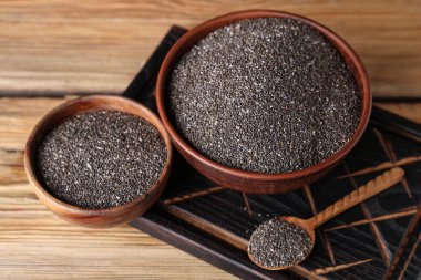 Ahşap zemin üzerinde chia tohumları olan kaseler ve kaşıklar.