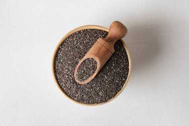 Beyaz zemin üzerinde chia tohumları olan kase ve ahşap kepçe