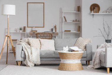 Masanın üzerinde gri kanepeler ve Noel dallarıyla aydınlık oturma odasının içinde.