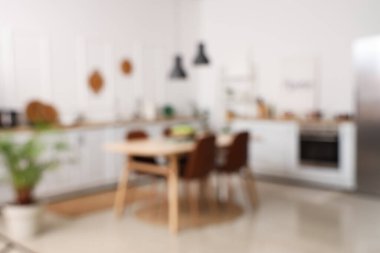 Yemek masası, beyaz tezgah ve raf ünitesiyle mutfağın bulanık görüntüsü