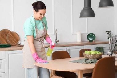 Mutfakta yemek masasını temizleyen genç bir kadın.