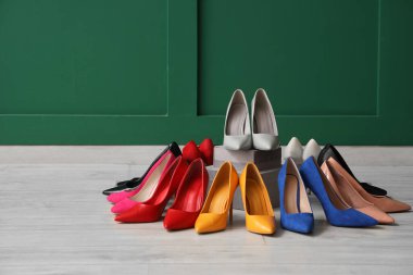 Yeşil duvarın yanında kutuları olan şık topuklu ayakkabılar.