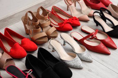 Aydınlık duvarın yanında farklı kadın ayakkabıları, yakın plan.