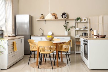 Mutfağın içinde yemek masası, tezgah ve raf ünitesi var.